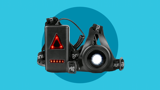 LUZ PECHERA PARA CORRER, un dispositivo wearable negro con correas ajustables y una brillante luz blanca central, presenta una caja de control rectangular negra con indicadores LED rojos de triángulo y barra, mostrados sobre un fondo azul.